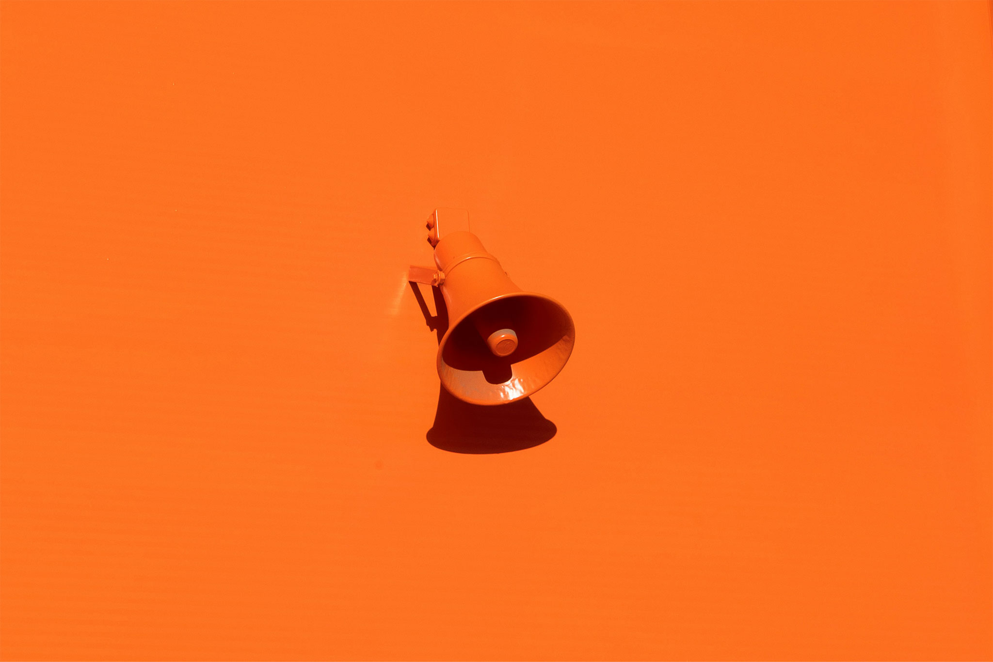 Orange wall-mounted loudspeaker on orange wall